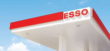 The roof of an Esso station in front of blue skies