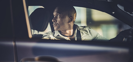 Man turned around inside of car for reverse manoeuvre.