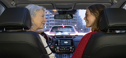 Photo of two women inside of a car smiling at each other